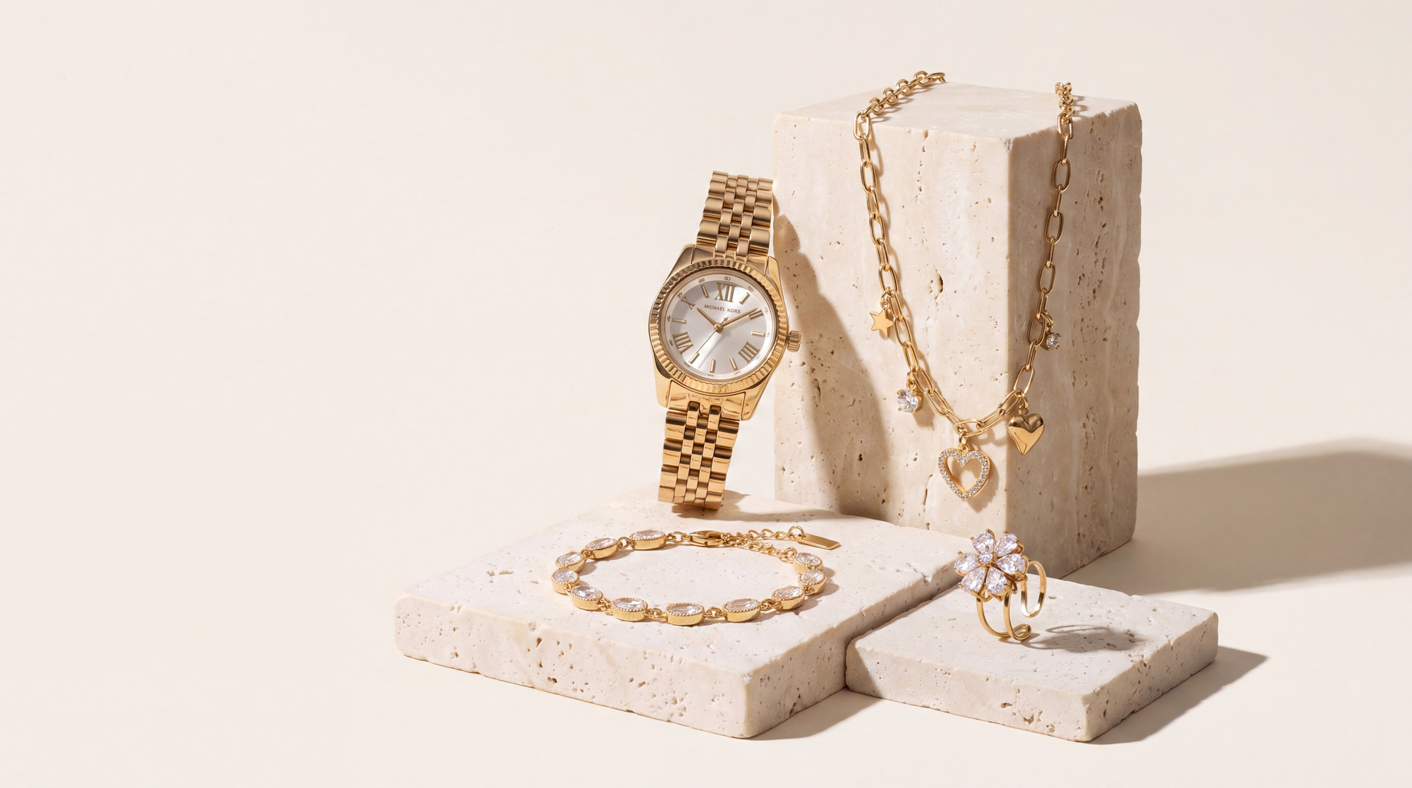 Montre Michael Kors Little Lexington doree et bijoux Maison Sveltesse sur socles de travertin ivoire