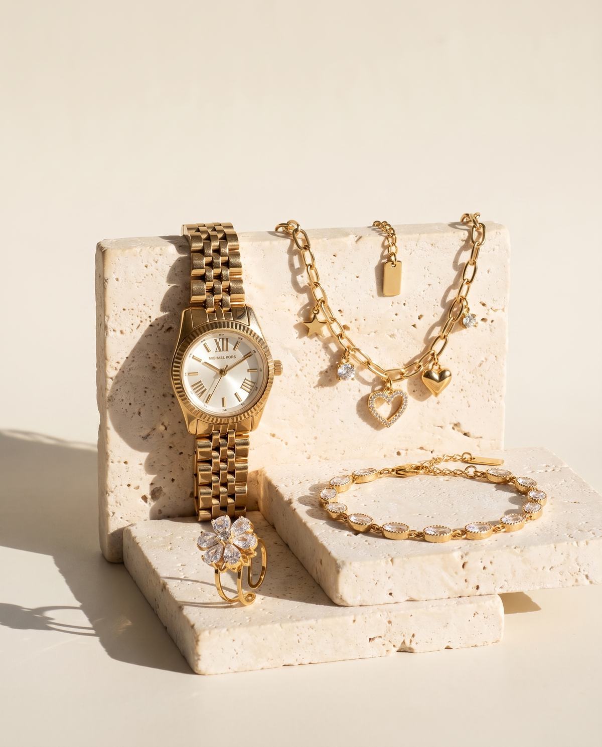 Montre Michael Kors Little Lexington doree et bijoux Maison Sveltesse sur socles de travertin ivoire, format mobile