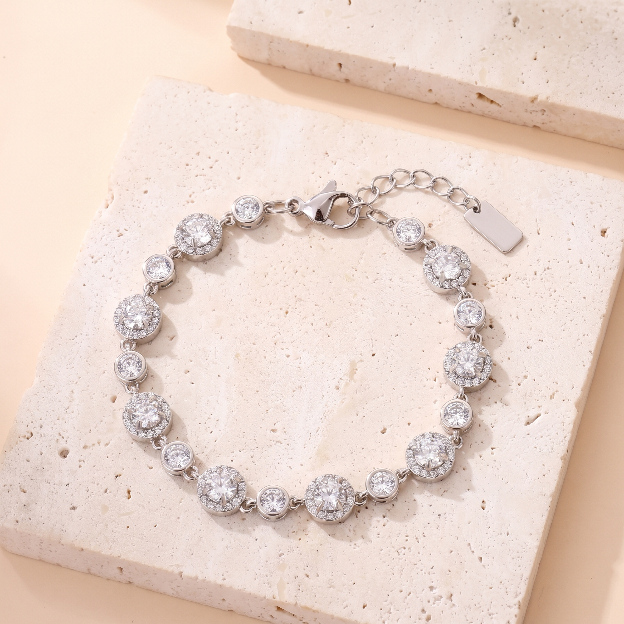 Bracelet Pleine Lune en acier inoxydable rhodié argenté, stations halo pavé et sertis clos, packshot sur travertin ivoire, Maison Sveltesse