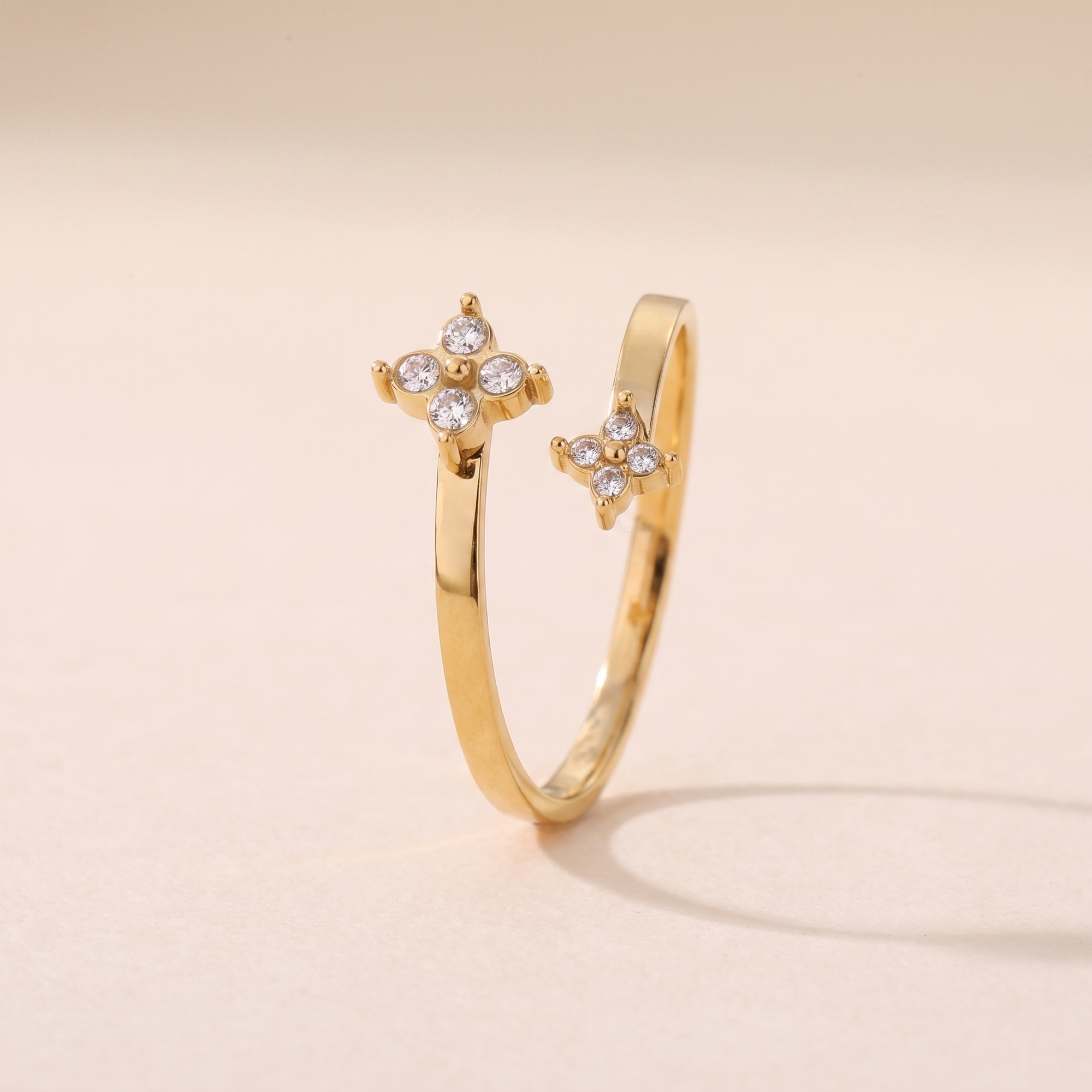 Bague Boréale en acier inoxydable doré, anneau croisé bypass à deux fleurs, packshot sur travertin ivoire, Maison Sveltesse