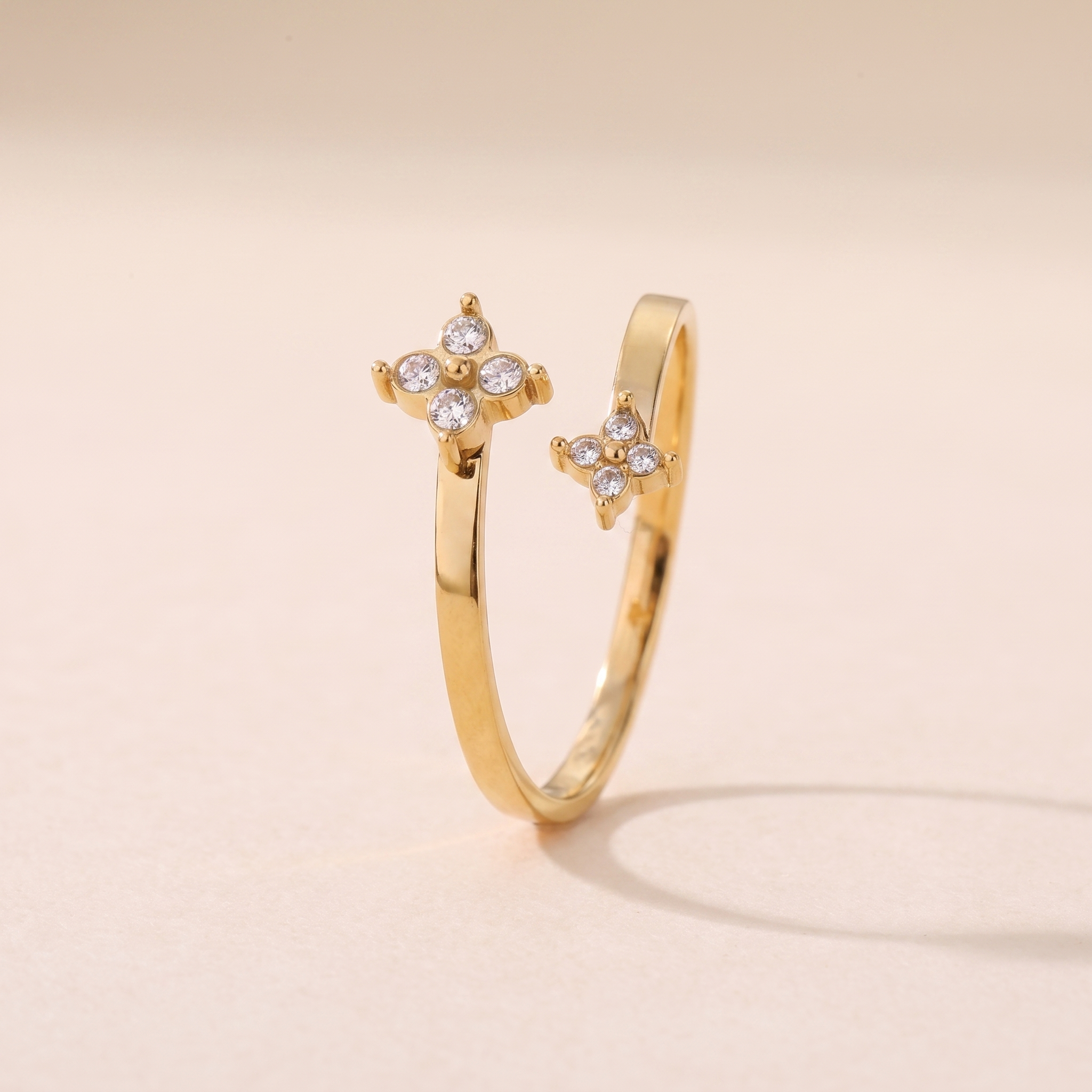Bague Boréale en acier inoxydable doré, anneau croisé bypass à deux fleurs, packshot sur travertin ivoire, Maison Sveltesse