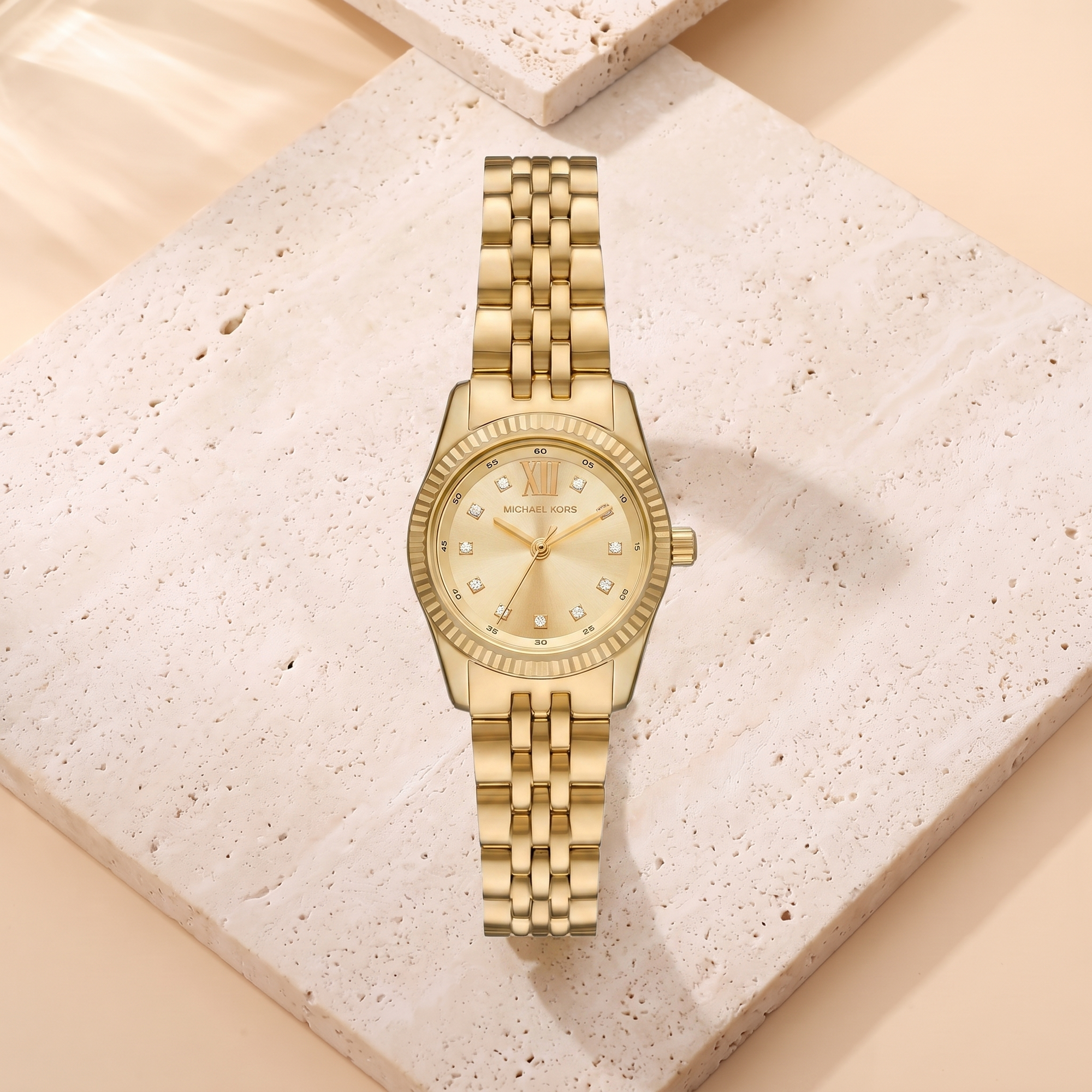 Montre Michael Kors Petite Lexington Gold, fond travertin